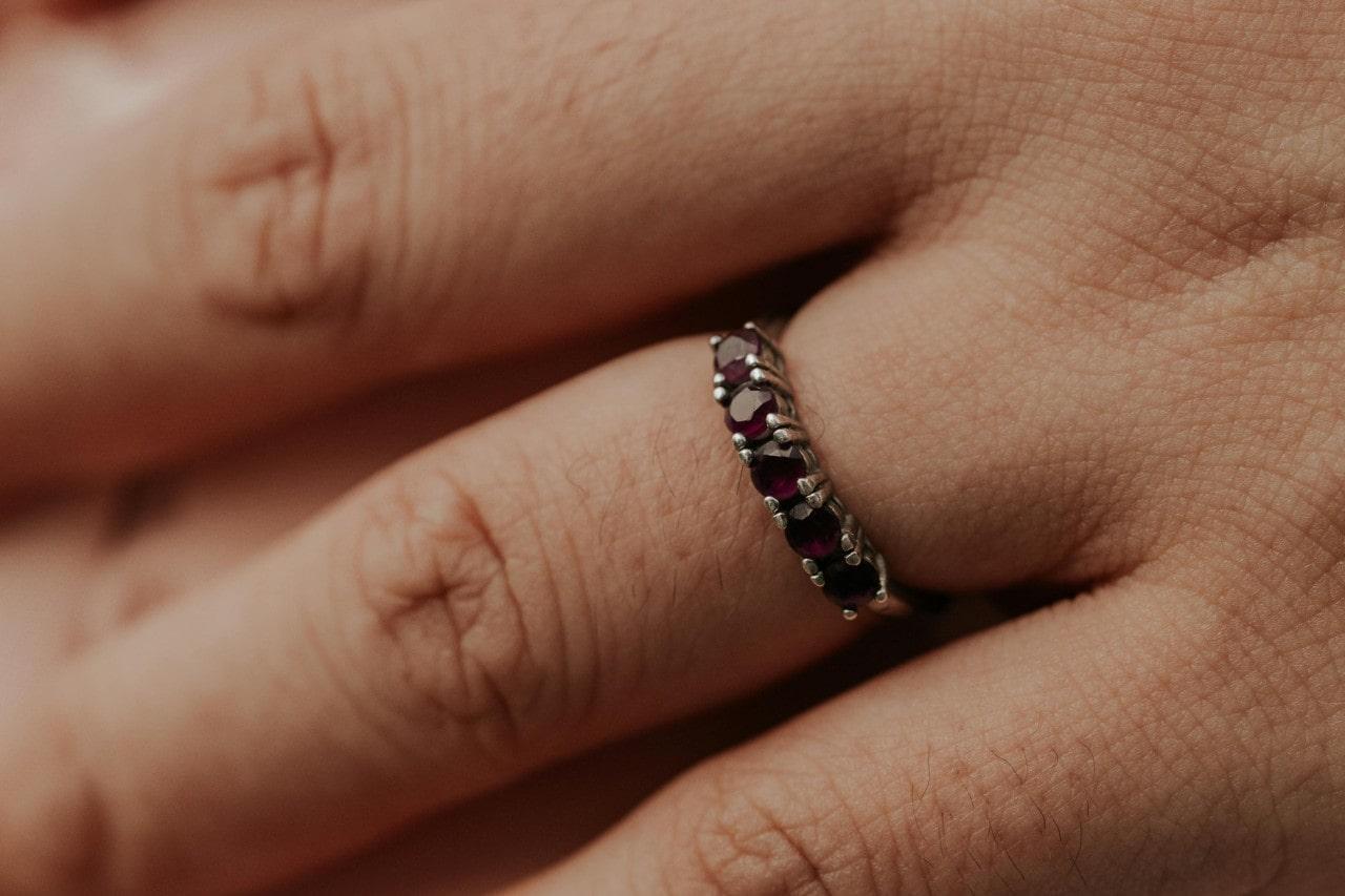 A close-up of an elegant ruby wedding band on a person’s finger.