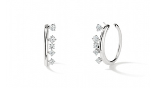 a pair of white gold huggie earrings featuring diamonds set askew on the hoop