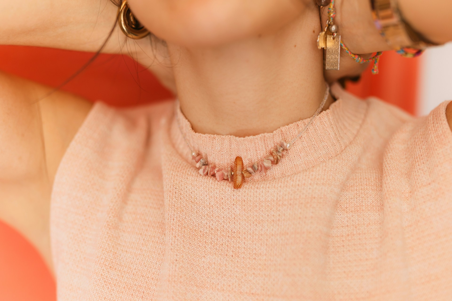 a lady putting on a pink necklace with beads