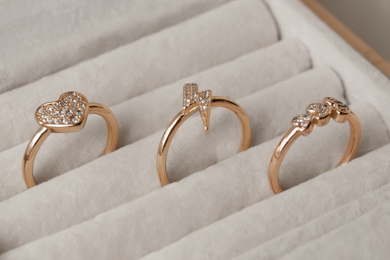 A close-up of three fashionable gold rings in a jewelry box.