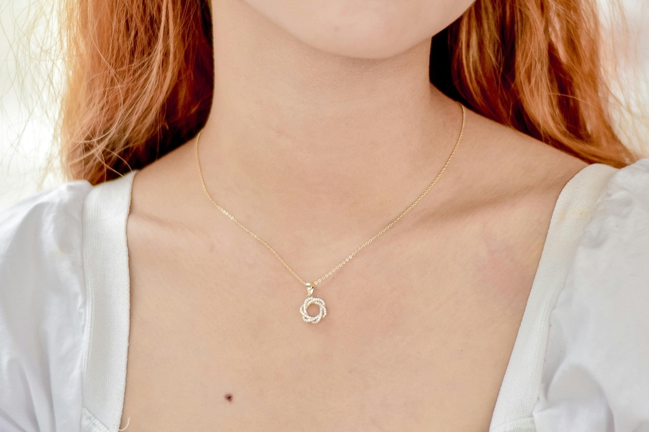 a woman wearing a delicate diamond pendant necklace