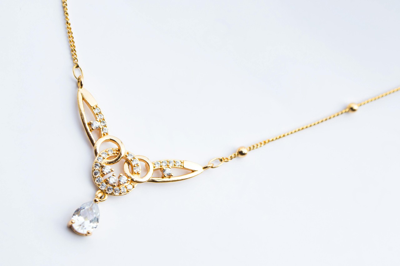 a yellow gold diamond necklace with a pear shape diamond centerpiece