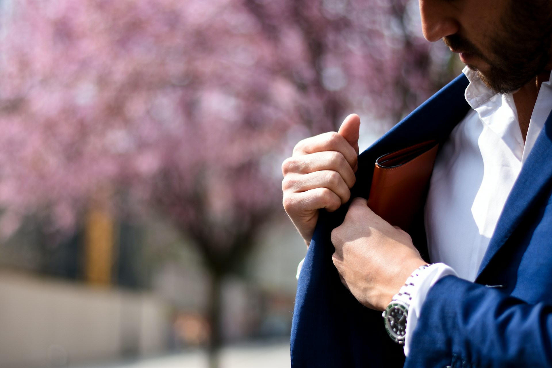 a man putting his wallet in his jacket pocket and wearing a black and silver watch