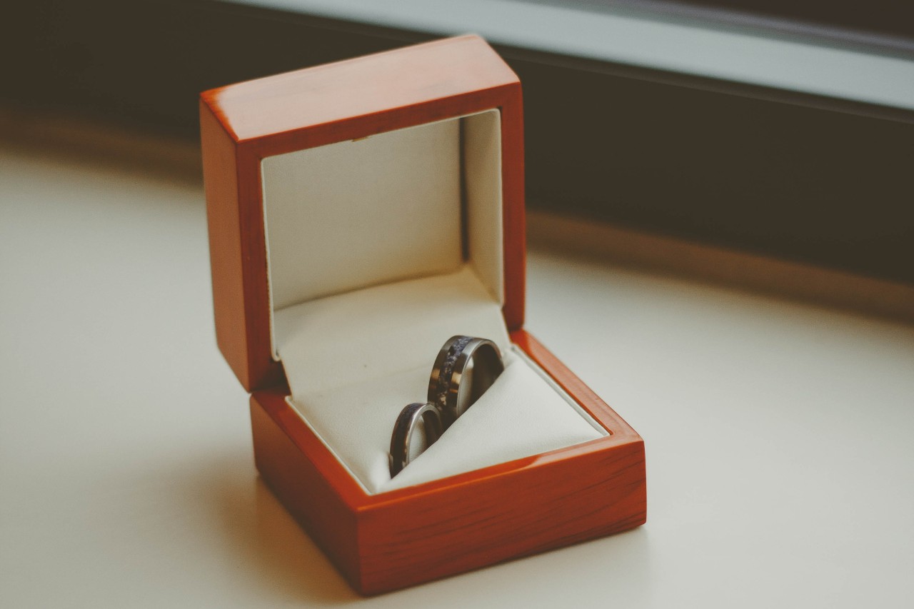 A matching pair of black wedding bands displayed in an elegant wooden box.