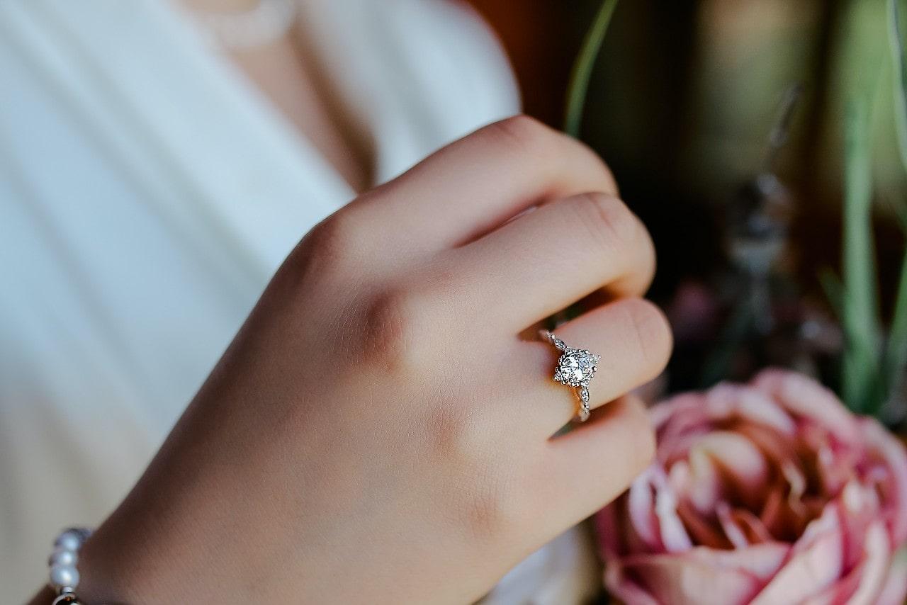 A close-up of a woman’s hand, wearing an elegant platinum engagement ring.